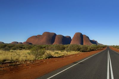 Empty road in desert against clear blue sky