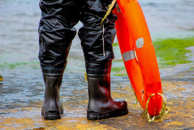 Low section of man with life belt at beach