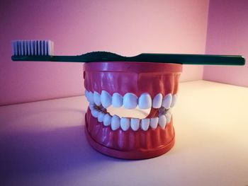 Close-up of dentures with toothbrush on table