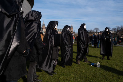 Rear view of people standing on street against sky