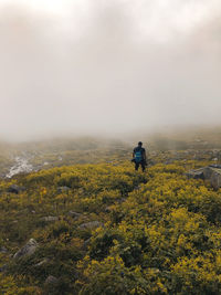 Rear view of man standing on mountain against sky