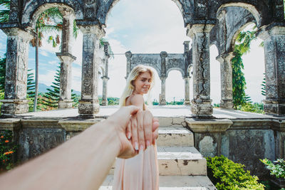 Young woman holding hand at abandoned structure