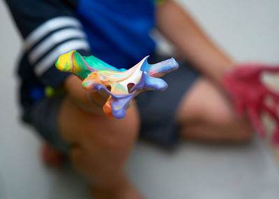 Close-up of hand holding toy against white background