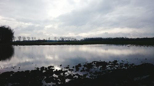 Scenic view of calm lake against cloudy sky