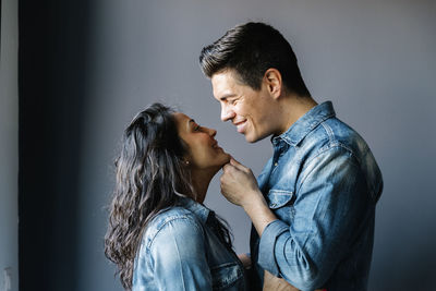 Side view of couple kissing against gray background