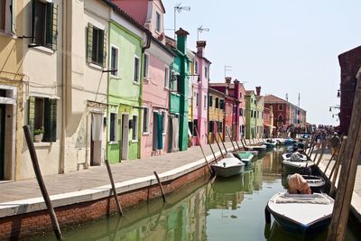 Boats moored in canal amidst buildings in city