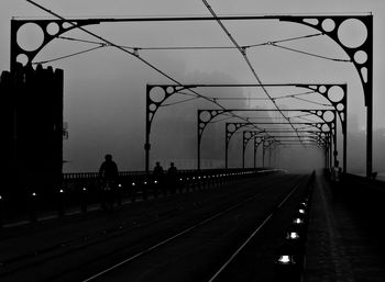 Silhouette people walking on railway bridge at night