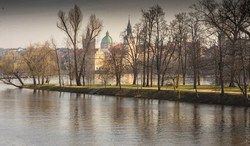 Trees and building by river against sky