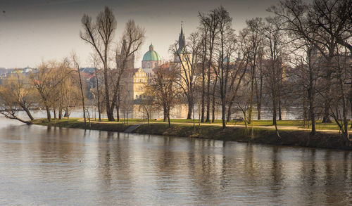 Trees and building by river against sky