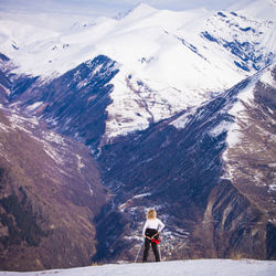 Rear view of woman standing against snowcapped mountains