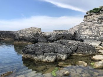 Rock formation by lake against sky