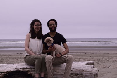 Portrait of friends sitting with dog at beach