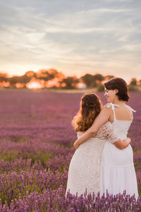 Rear view of lesbian couple standing on flower field