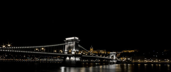 Panoramic view of illuminated chain bridge over river against clear sky at night in city