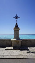 Lighthouse in sea against clear blue sky