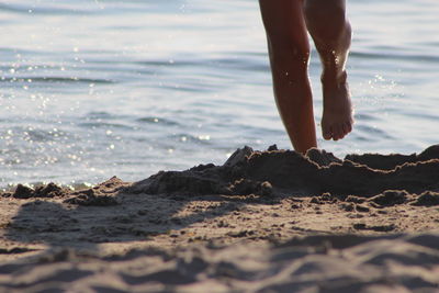 Low section of woman running at beach