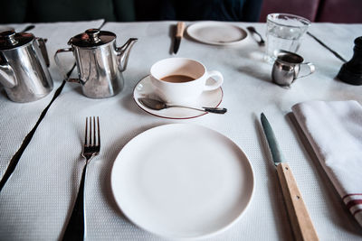 High angle view of empty plate by coffee and kettles on table
