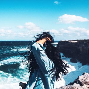 Woman standing in sea against sky