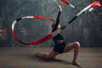 Woman with arms raised standing against wall