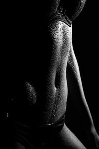 Midsection of woman sweating against black background