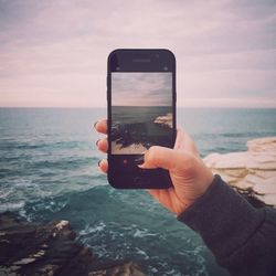 Man photographing sea against sky