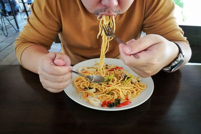 Midsection of man holding food while sitting on table