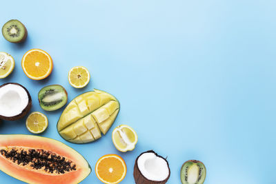 Different fresh tropical cut fruits on a blue background. top view flat lay with copy space for text