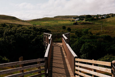 Footbridge over mountain against sky
