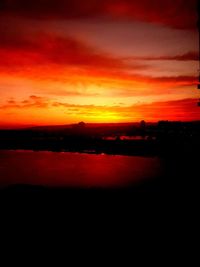 Scenic view of dramatic sky over silhouette landscape during sunset