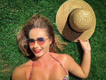 Portrait of happy young woman lying down on the green grass