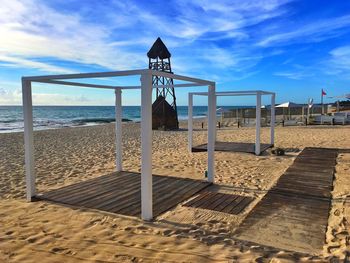 Huts at sandy beach against sky