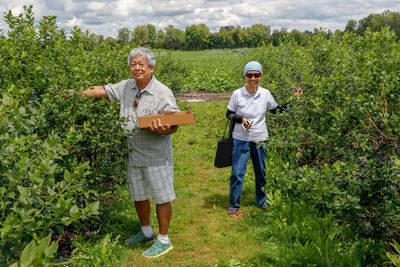 Full length portrait of a smiling young couple standing in farm