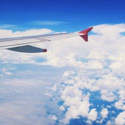 Airplane flying over clouds against blue sky