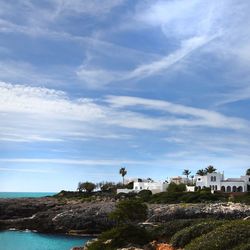 Buildings by sea against sky