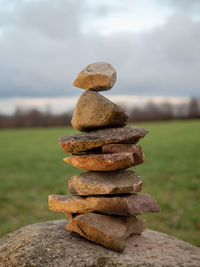 Stack of stones on field against sky