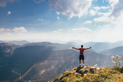 Rear view of man standing on mountain against sky