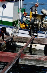 Fishermen using machinery on boat at sea