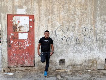 Portrait of young man standing against wall