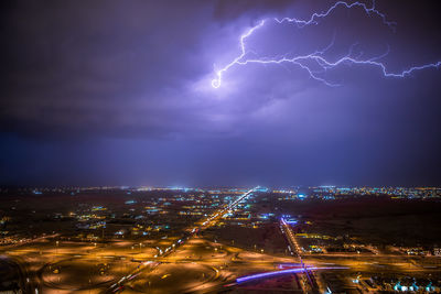 Lightning strike over illuminated cityscape