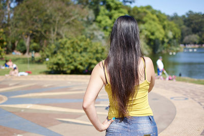 Rear view of woman with umbrella against trees