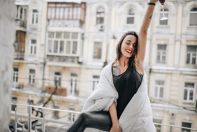 Happy woman standing against building in city