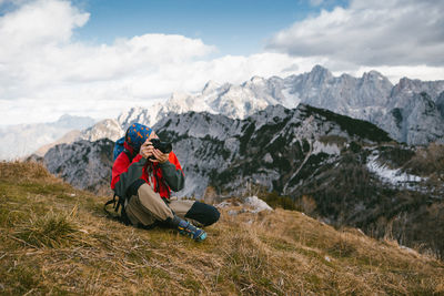 Woman photographing on mountain against sky