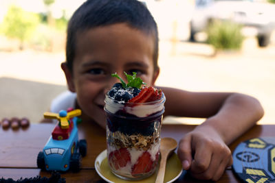 Portrait of boy sitting by ice cream on table