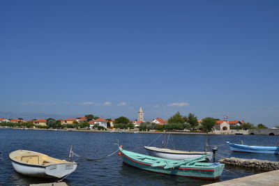 Boats moored in sea against blue sky