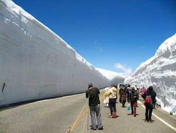 Tourists walk along snow corridor on tateyama kurobe alpine route, japanese alp in tateyama, japan.