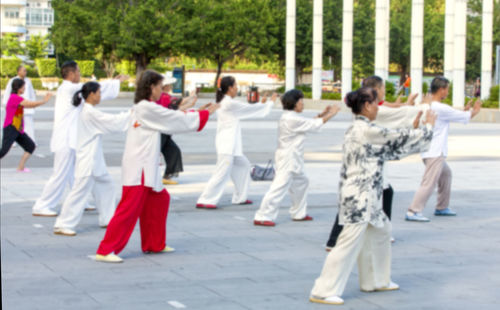 Rear view of people walking on footpath in city