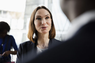 Smiling businesswoman talking to male delegate at seminar in convention center