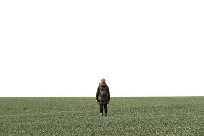 Rear view of man standing on field against clear sky