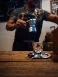 Close-up of man holding coffee cup on table
