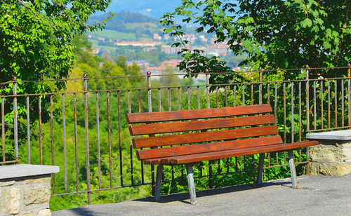 Empty benches by plants against sky